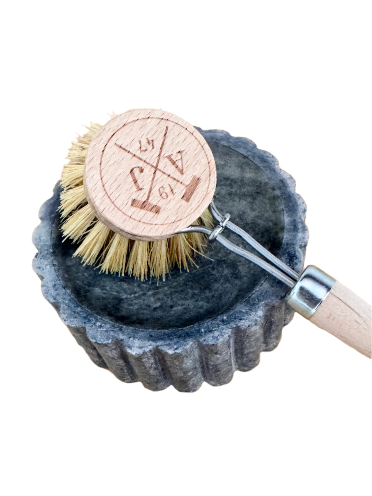 Dish brush with wooden handle and bristles in a stone holder on a wooden surface