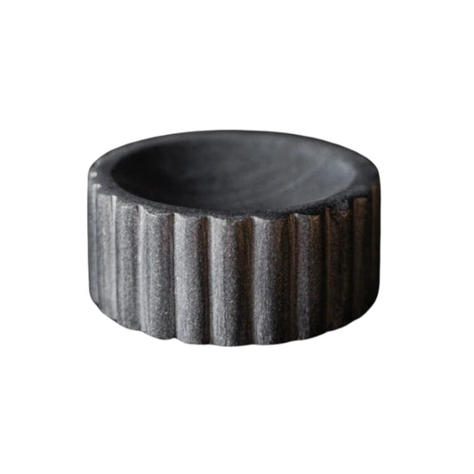 Black stone bowl with textured surface on a white background