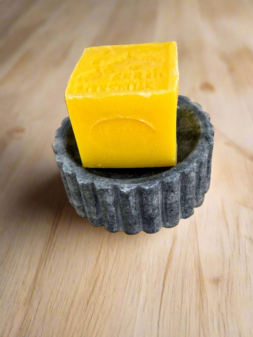 Yellow block of soap with a gear-shaped holder on cardboard